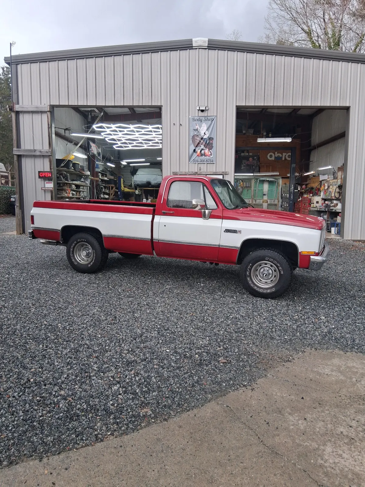 Vintage red and white pickup parked outside repair shop bays — The ARK Body Shop and Collision Center in Concord